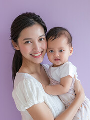 A smiling Thai mother in a white T-shirt with her baby in her arms