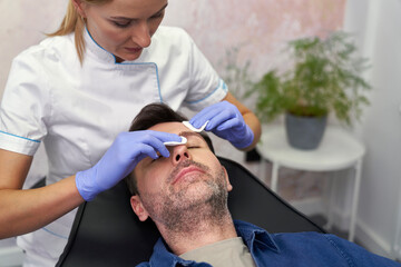 Beautician cleaning man's face before the beauty procedure - 787187838