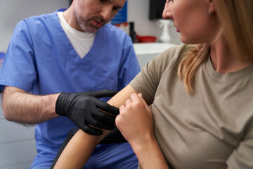 Doctor checking mark on woman's arm - 787188290
