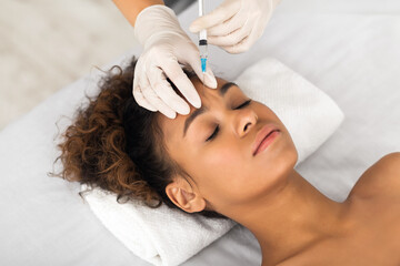 Obraz na płótnie Canvas African american woman receiving facial injection treatment