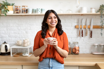 Cheerful middle eastern woman standing in modern kitchen