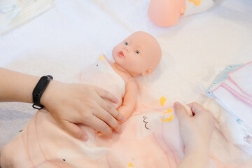 New mother receives training in swaddling newborn baby with baby doll