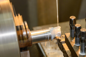 The lathe machine finish cut the metal shaft parts with liquid coolant method.