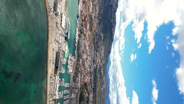 Aerial view of Denia city. Drone going forward and panning right. Travel destination and point of departure for ferry boats for visiting the Balearic Islands. 