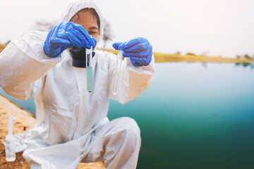Scientists with protective suit holding a test tube with sample water in her hands. Water pollution examine concept	