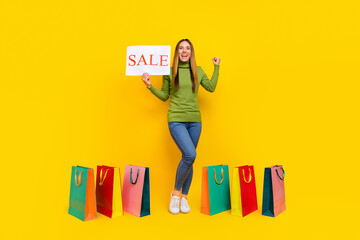 Full body portrait of delighted person raise fist demonstrate sale news isolated on yellow color...