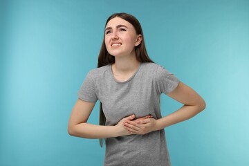 Woman having heart attack on light blue background