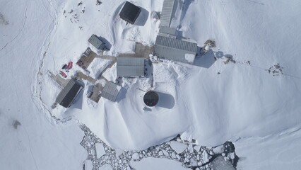 Aerial drone view flight. Vernadsky Base, ocean, mountains. Fast. The station settlement on the...