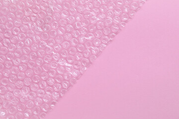 Transparent bubble wrap on pink background, top view. Space for text