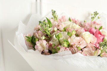 Beautiful bouquet of fresh flowers near white wall, closeup