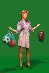 Young woman in silky bathrobe with hair curlers holding boxing gloves and sport balls against vibrant green background. Concept of sport, competition, active lifestyle, hobby, recreation. Ad