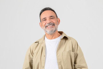 Senior smiling with hands in pockets on white background