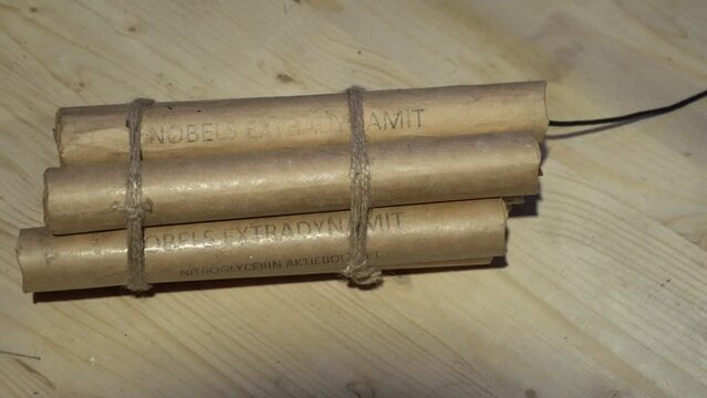 Male hands put a bundle of dynamite with a wick on the table.