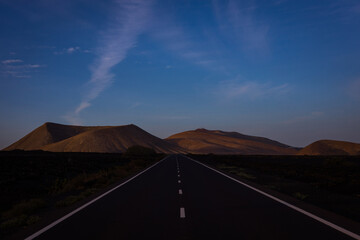 Long empty street between lava fields leading from Yaiza to the volcanic territory of Timanfaya...
