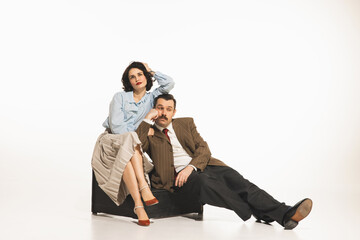 Young couple, man and woman in retro clothes sitting with bored faces isolated on white background....