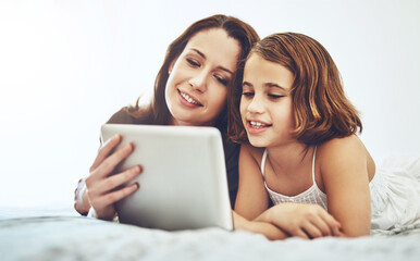 Fototapeta premium Smile, mother and child on tablet in bedroom at home together for game, relax and family streaming movie. Happy girl, mom and technology in bed for learning, education or reading ebook on app online
