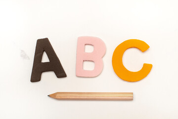 Letras del alfabeto A B C junto a un lápiz sobre un fondo blanco aislado. Vista superior y de cerca. Copy space - 787227295