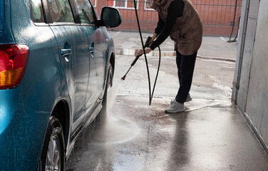 Woman washing her car in a self-service car wash station.Car wash self-service.
