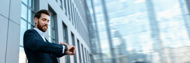 Smiling confident handsome young european man looks at watch