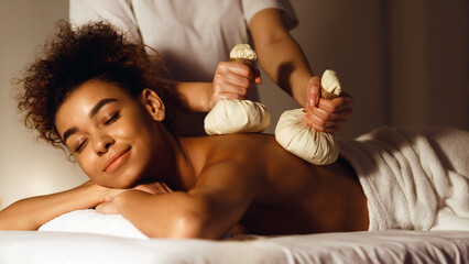 Thai herb compress massage. Woman relaxing in beauty spa