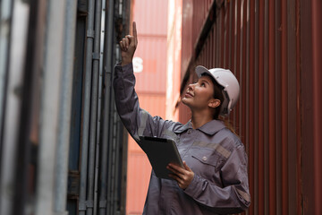 Female container yard worker loading containers box at commercial dock site. Female worker control loading container box from cargo freight ship for import export