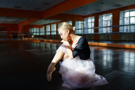 Fototapeta Pensive ballerina sitting on floor in ballet studio