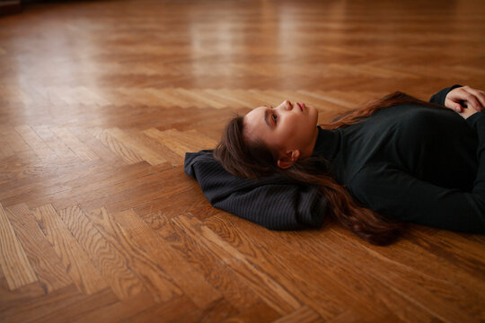 Pensive woman lying on parquet floor