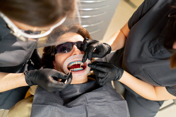dental office girl dentist applies protective gel to the gums of young guy