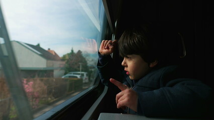 Fototapeta na wymiar Small Boy Seated by Train Window, Observing Passing Landscape Scenery and Squinting Eyes to Protect Against Sunrays, 5-Year-Old Caucasian Kid Traveler