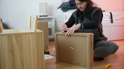 Woman assembling furniture, person moving to new home assembly. DIY improvement