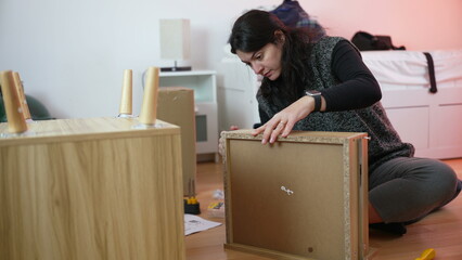 Woman assembling furniture, person moving to new home assembly. DIY improvement