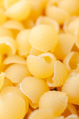 Uncooked, yellow, small shell shaped pasta background. Top view. Close-up