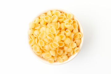 Yellow, small shell shaped pasta in bowl on white background. Top view