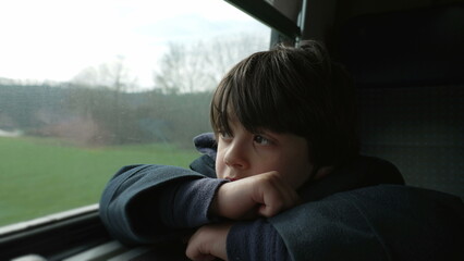 Thoughtful kid looking at scenery pass by from train. Contemplative 5 year old boy lost in thought...