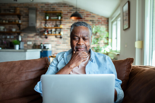 Senior African American man using laptop on sofa at home