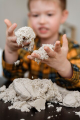 A small child plays in the sandbox at home. Boy makes sand molds