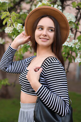 Fototapeta premium Beautiful woman in hat near blossoming tree on spring day