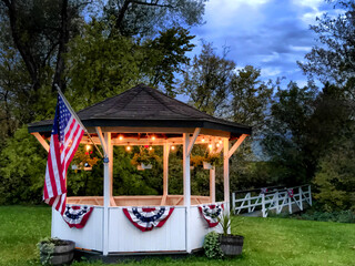 Gazebo in the country decorated with red, white, and blue bunting and an American flag