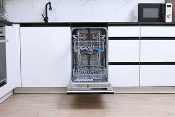 Open clean empty dishwasher in kitchen. Home appliance