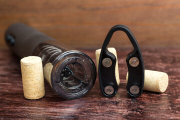 An electric corkscrew and wine bottle caps lie dark wood table, preparing for the holiday. - obrazy, fototapety, plakaty