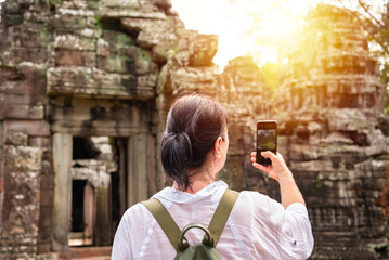 Female tourist taking photo of ancient Angkor temple in Cambodia