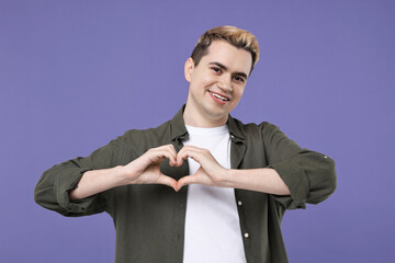 Young man showing heart gesture with hands on purple background