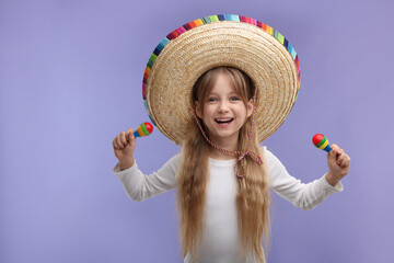 Cute girl in Mexican sombrero hat with maracas on purple background