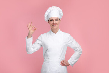 Happy chef in uniform showing OK gesture on pink background