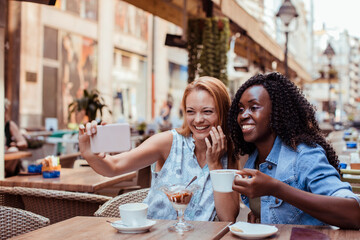 Two young women taking selfie in street cafe