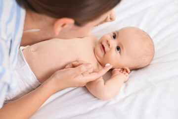 Obraz na płótnie Canvas Woman applying cream onto baby`s face on bed, closeup