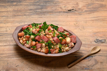 Feijão tropeiro in a wooden container, typical food from Minas Gerais, Brazil, wooden base	