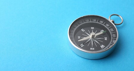 One compass on light blue background, closeup. Space for text
