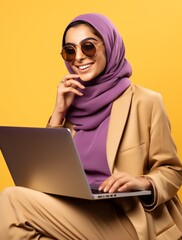 A woman in a hijab is typing on a laptop