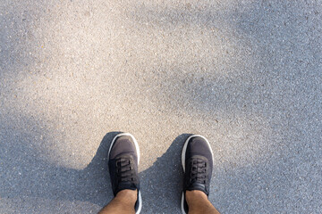 Fitness and healthy lifestyle concept. Man looking running sneakers on a asphalt road in the...